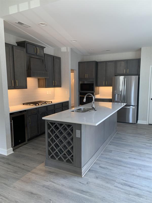 Dark gray kitchen cabinets with a gray island and built-in wine rack