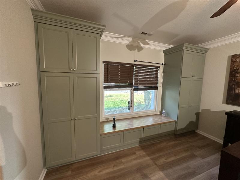 Sage green built-in tall cabinets framing a window seat