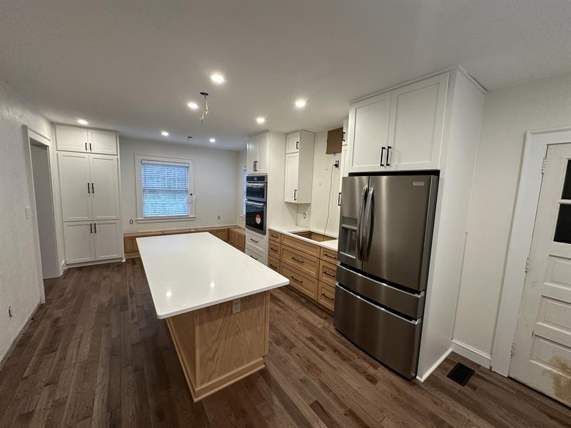 White and natural oak kitchen cabinets with an island and tall pantry cabinets