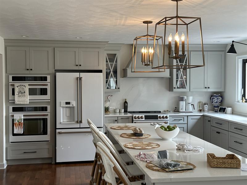 Gray painted kitchen cabinets with an island and built-in wall ovens