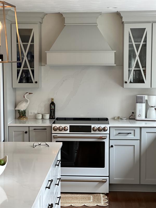 Painted range hood flanked by glass-front cabinets with X mullions