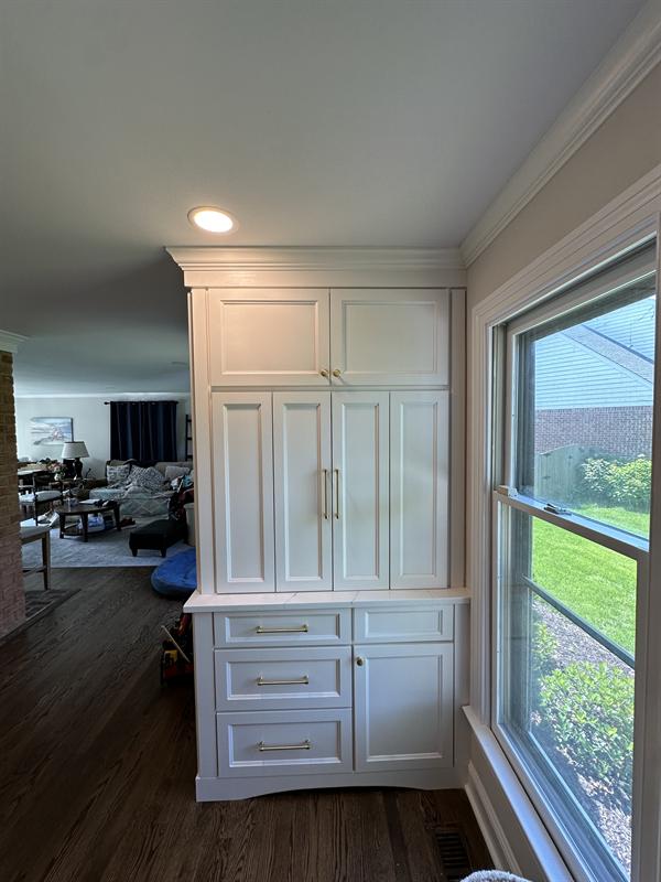 White built-in pantry hutch beside a window